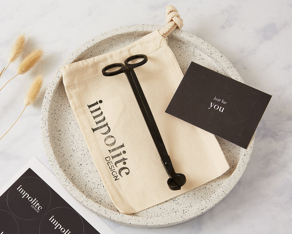 Black stainless steel candle wick trimmers in a reusable environmentally friendly cotton bag